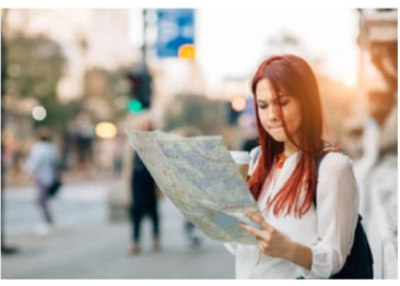 Person on a street looking at a paper map, unsure where to go